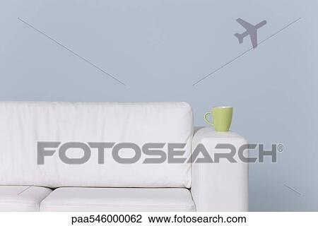 Mug on arm of sofa, airplane shape in background View Large Photo Image Stock Image - Mug on arm of sofa, airplane shape in background. Fotosearch