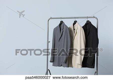 Three men's suit jackets hanging on clothes rack, airplane shape in background View Large Photo Image Stock Photo - Three men's suit jackets hanging on clothes rack, airplane shape in background. Fotosearch