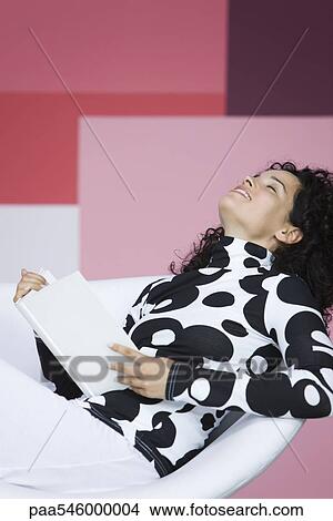 Woman enjoying book, leaning back with eyes closed, smiling View Large Photo Image Picture - Woman enjoying book, leaning back with eyes closed, smiling. Fotosearch