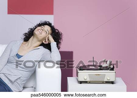 Stock Photography - Woman enjoying music, listening to old-fashioned record player. Fotosearch