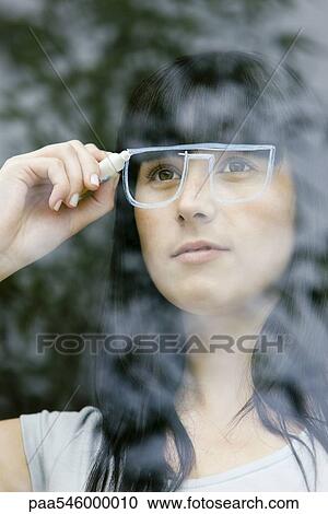 Young woman drawing a pair of glasses on a window pane, looking through window View Large Photo Image Stock Image - Young woman drawing a pair of glasses on a window pane, looking through window. Fotosearch