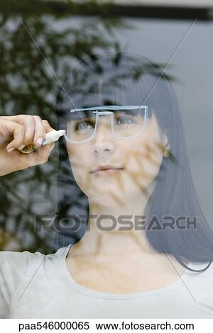 Young woman drawing a pair of glasses on a window pane, looking through window View Large Photo Image Stock Photography - Young woman drawing a pair of glasses on a window pane, looking through window. Fotosearch