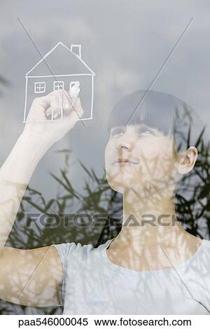 Young woman drawing house on windowpane, daydreaming View Large Photo Image Stock Photography - Young woman drawing house on windowpane, daydreaming. Fotosearch