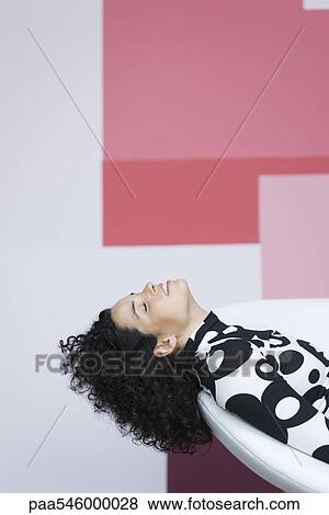 Young woman sitting with head back, relaxing View Large Photo Image Stock Photo - Young woman sitting with head back, relaxing. Fotosearch