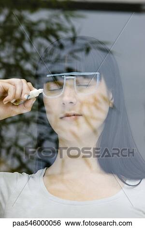 Young woman with eyes closed, drawing pair of glasses on window View Large Photo Image Stock Photograph - Young woman with eyes closed, drawing pair of glasses on window. Fotosearch