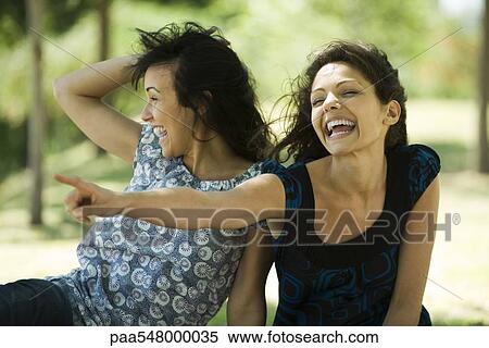 "Two young women laughing outdoors, one pointing" View Large Photo Image Stock Photography - "Two young women laughing outdoors, one pointing". Fotosearch
