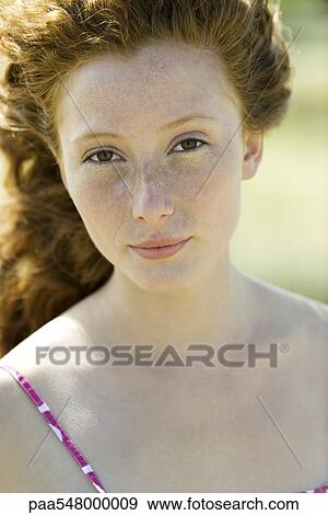 Stock Photo - "Young red haired woman looking at camera, portrait". Fotosearch