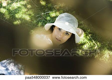 "Young woman in sun hat lying on ground, looking at camera, selective focus" View Large Photo Image Stock Photo - "Young woman in sun hat lying on ground, looking at camera, selective focus". Fotosearch