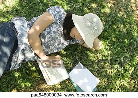 "Young woman lying on the ground reading, high angle view" View Large Photo Image Picture - "Young woman lying on the ground reading, high angle view". Fotosearch