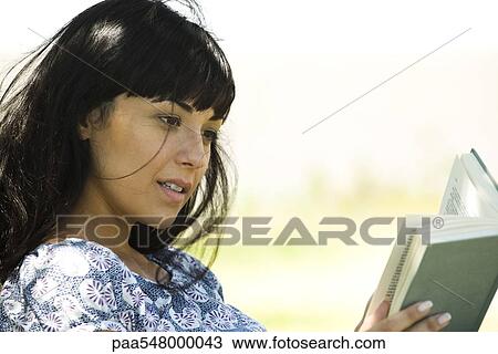 Young woman reading book outdoors View Large Photo Image Stock Image - Young woman reading book outdoors. Fotosearch