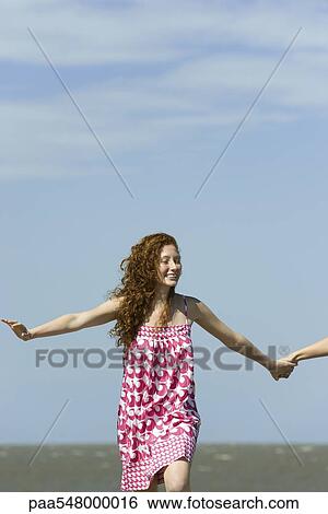 "Young woman running with arms out, holding friend's hand, cropped" View Large Photo Image Stock Photograph - "Young woman running with arms out, holding friend's hand, cropped". Fotosearch