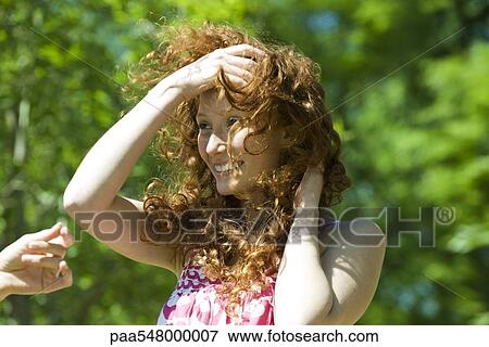 Stock Photo - Young woman with red hair outdoors on windy day. Fotosearch