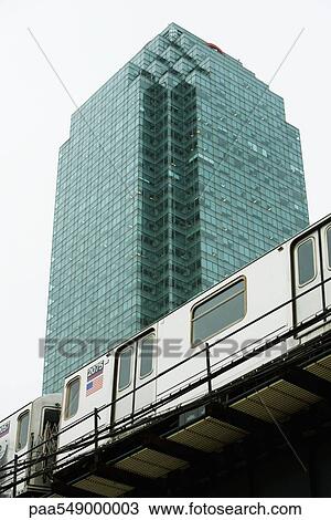 Stock Image - "Elevated subway, office building in background, low angle view". Fotosearch