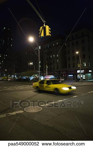 Stock Image - Taxi speeding through intersection at night. Fotosearch