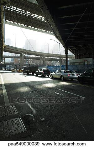 Traffic waiting at traffic signal on street beneath elevated road View Large Photo Image Stock Photo - Traffic waiting at traffic signal on street beneath elevated road. Fotosearch