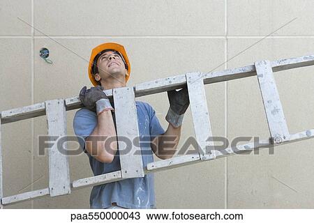 Stock Image - "Construction worker carrying ladder, looking up". Fotosearch
