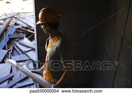 Construction worker carrying scrap wood cleaning up construction site View Large Photo Image Picture - Construction worker carrying scrap wood cleaning up construction site. Fotosearch