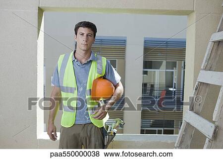 Stock Photo - Construction worker holding hard hat under arm looking at camera. Fotosearch