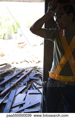 Stock Photo - "Construction worker pausing work, hand on forehead". Fotosearch