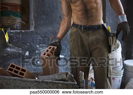 Stock Photograph - Construction worker placing bricks into wheelbarrow. Fotosearch