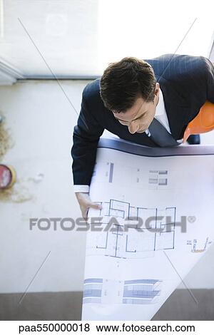 Man in suit reviewing blueprint View Large Photo Image Stock Photo - Man in suit reviewing blueprint. Fotosearch