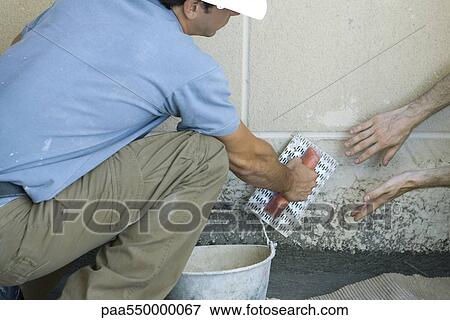 Stock Photo - Mason receving guidance on proper masonry technique. Fotosearch