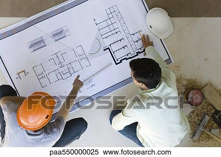 Two men reviewing blueprint spread out on floor View Large Photo Image Stock Photography - Two men reviewing blueprint spread out on floor. Fotosearch