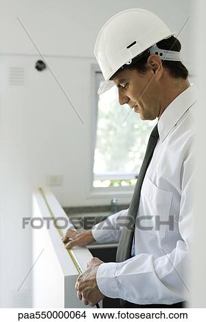 Picture - Well-dressed man measuring ledge length. Fotosearch