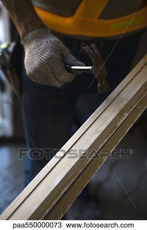 Stock Image - Worker holding hammer against wood. Fotosearch
