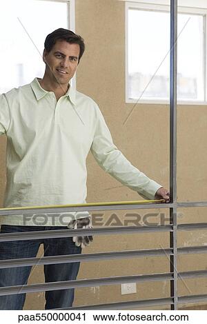 "Worker standing at interior railing measuring bannister, smiling at camera" View Large Photo Image Stock Image - "Worker standing at interior railing measuring bannister, smiling at camera". Fotosearch