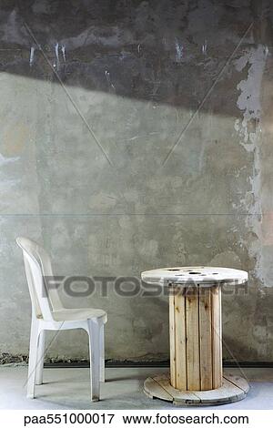 Plastic chair set before wooden reel table in unfinsihed room View Large Photo Image Stock Photo - Plastic chair set before wooden reel table in unfinsihed room. Fotosearch