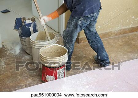 Picture - Worker mixing plaster in bucket. Fotosearch
