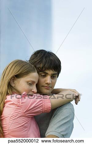 "Young couple embracing, looking down" View Large Photo Image Stock Image - "Young couple embracing, looking down". Fotosearch