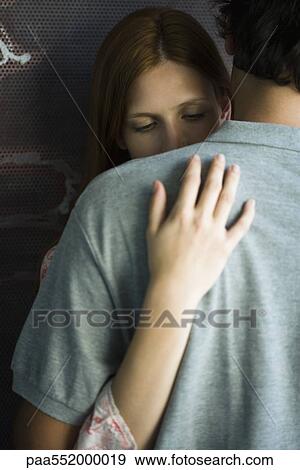 Stock Photo - "Young couple embracing stiffly, woman looking down". Fotosearch