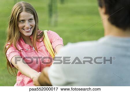 Stock Photo - "Young couple face to face, holding hands, cropped view". Fotosearch