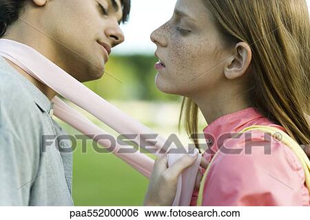 Stock Photograph - "Young couple leaning in to kiss, eyes closed, side view". Fotosearch