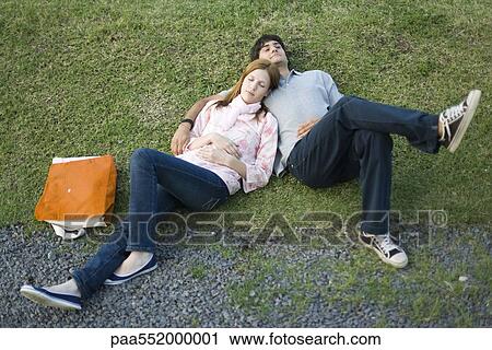 "Young couple lying together on grass, high angle view" View Large Photo Image Stock Image - "Young couple lying together on grass, high angle view". Fotosearch