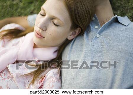 Stock Photography - "Young couple napping on ground, woman's head resting on man's chest". Fotosearch