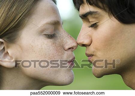 Stock Photo - "Young couple touching noses, puckering, profile". Fotosearch