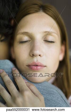 Stock Image - "Young woman embracing man, eyes closed, close-up". Fotosearch