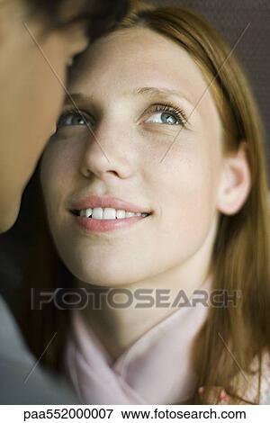 Stock Photo - "Young woman face to face with man, looking up hopefully, smiling". Fotosearch