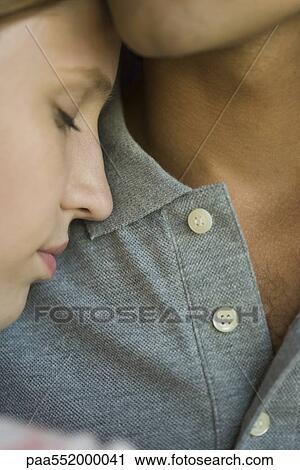 Stock Image - "Young woman leaning head against man's chest, eyes closed, close-up". Fotosearch