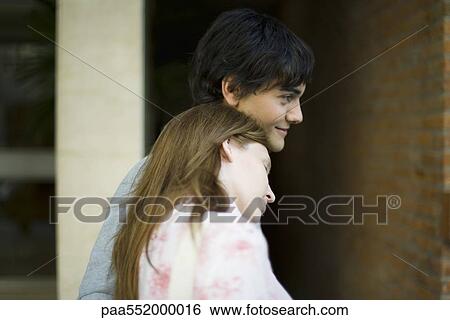 Stock Photograph - "Young woman leaning head on boyfriend's shoulder, side view". Fotosearch