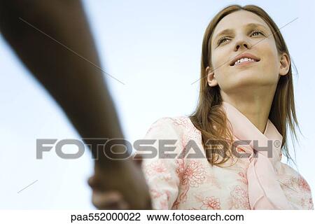 "Young woman shaking man's hand, cropped, low angle view" View Large Photo Image Stock Image - "Young woman shaking man's hand, cropped, low angle view". Fotosearch