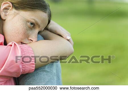 "Young woman sitting outdoors with head resting on arms, looking away" View Large Photo Image Stock Image - "Young woman sitting outdoors with head resting on arms, looking away". Fotosearch