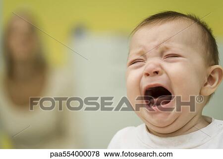 Baby crying, mother in background View Large Photo Image Stock Photo - Baby crying, mother in background. Fotosearch