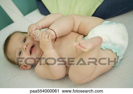 Baby lying on back, playing with foot View Large Photo Image Stock Image - Baby lying on back, playing with foot. Fotosearch