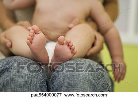 Baby sitting on mother's lap, cropped View Large Photo Image Stock Photo - Baby sitting on mother's lap, cropped. Fotosearch