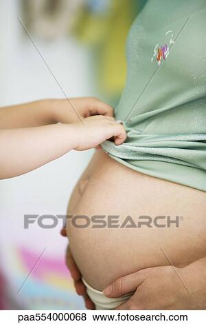 Child pulling mother's shirt down over pregnant belly View Large Photo Image Stock Photo - Child pulling mother's shirt down over pregnant belly. Fotosearch