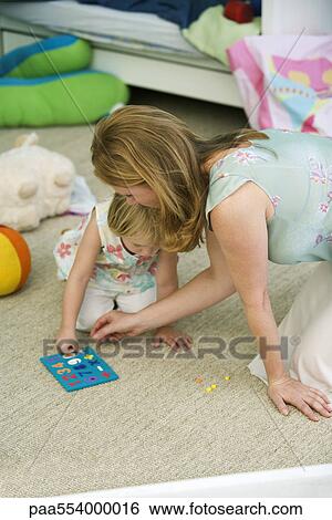 Stock Photograph - Mother and daughter playing together in child's bedroom. Fotosearch